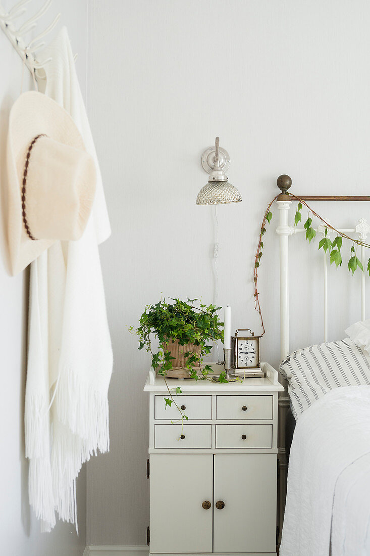 Potted ivy on bedside table in white bedroom