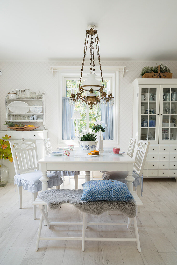 Bench and chairs around white table in vintage-style dining room