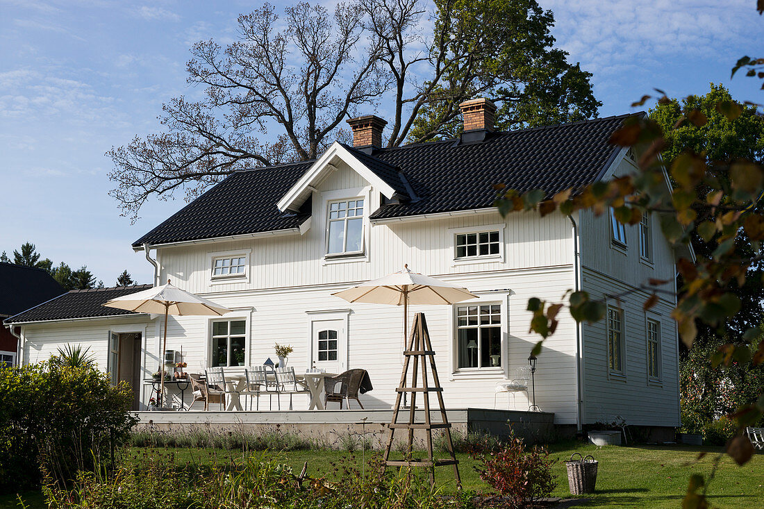 Weißes Schwedenhaus mit schwarzem Dach und Terrasse