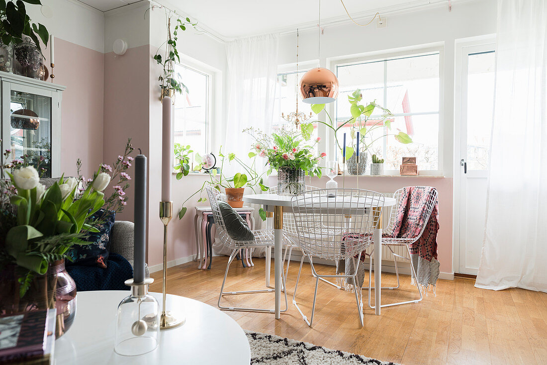 Delicate metal chairs around dining table in front of pink wall