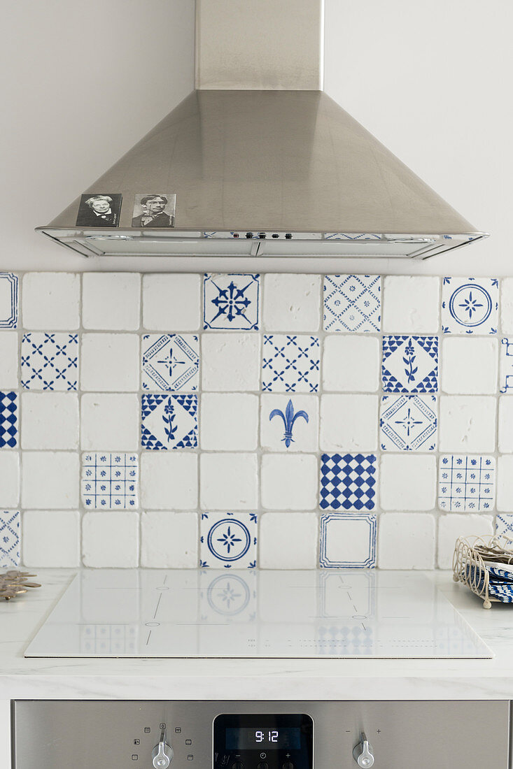 Extractor hood over cooker with hob cover and white and blue wall tiles in kitchen