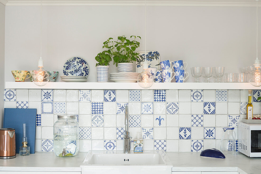 Weiß-blaue Wandfliesen und Regalbrett über Spülbecken in der Küche
