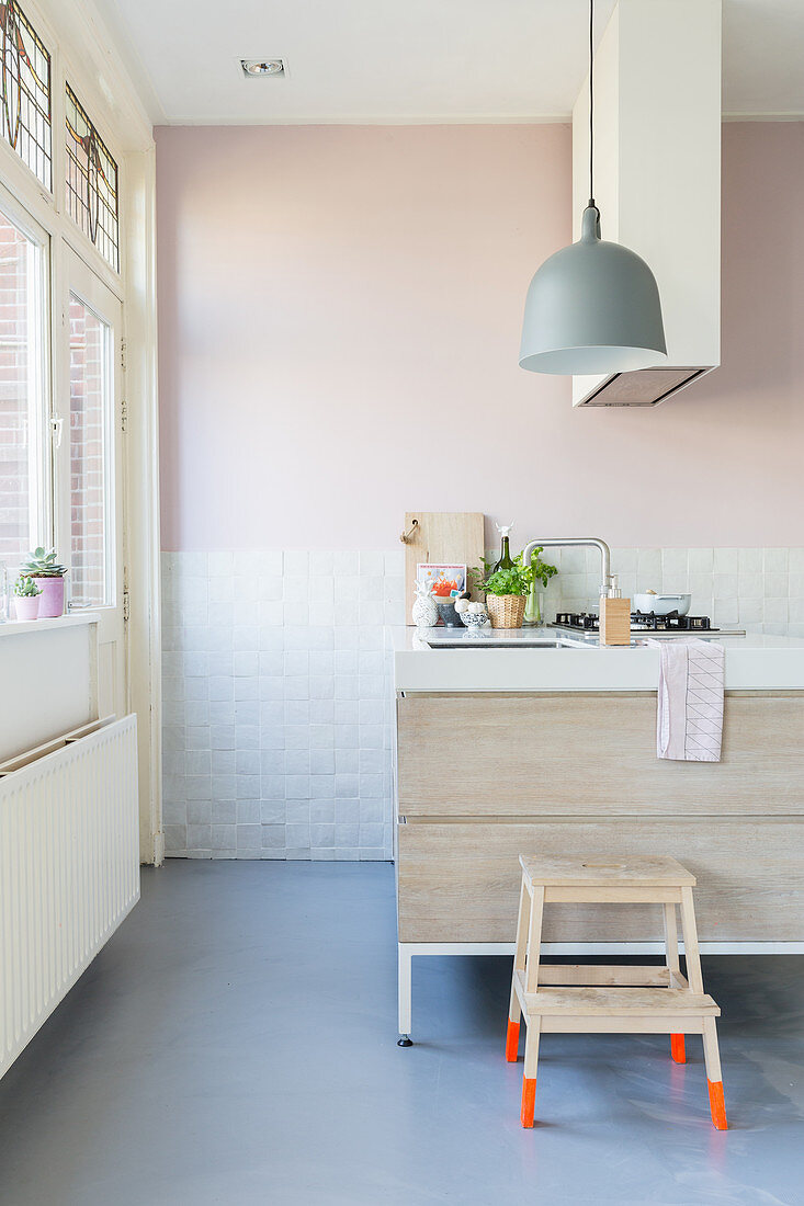 Hocker mit knallroten Füßen in einer pastellfarbenen, modernen Küche