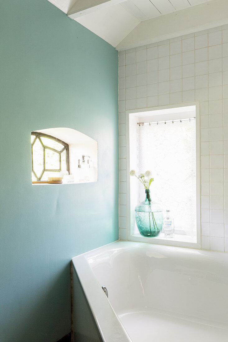 Hellblaue Wand mit kleinem Fenster im Bad mit Eckbadewanne