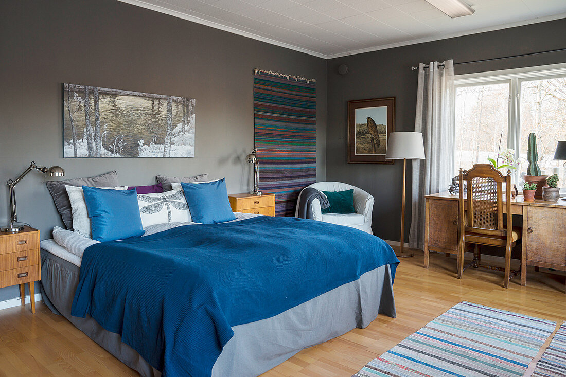 Blaue Decke auf dem Bett im Schlafzimmer mit grauen Wänden