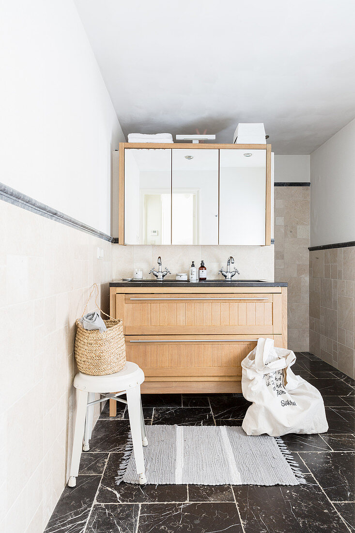 Waschbeckenunterbau mit Holzfront und Spiegelschrank im Bad mit schwarzen Marmor-Bodenflliesen