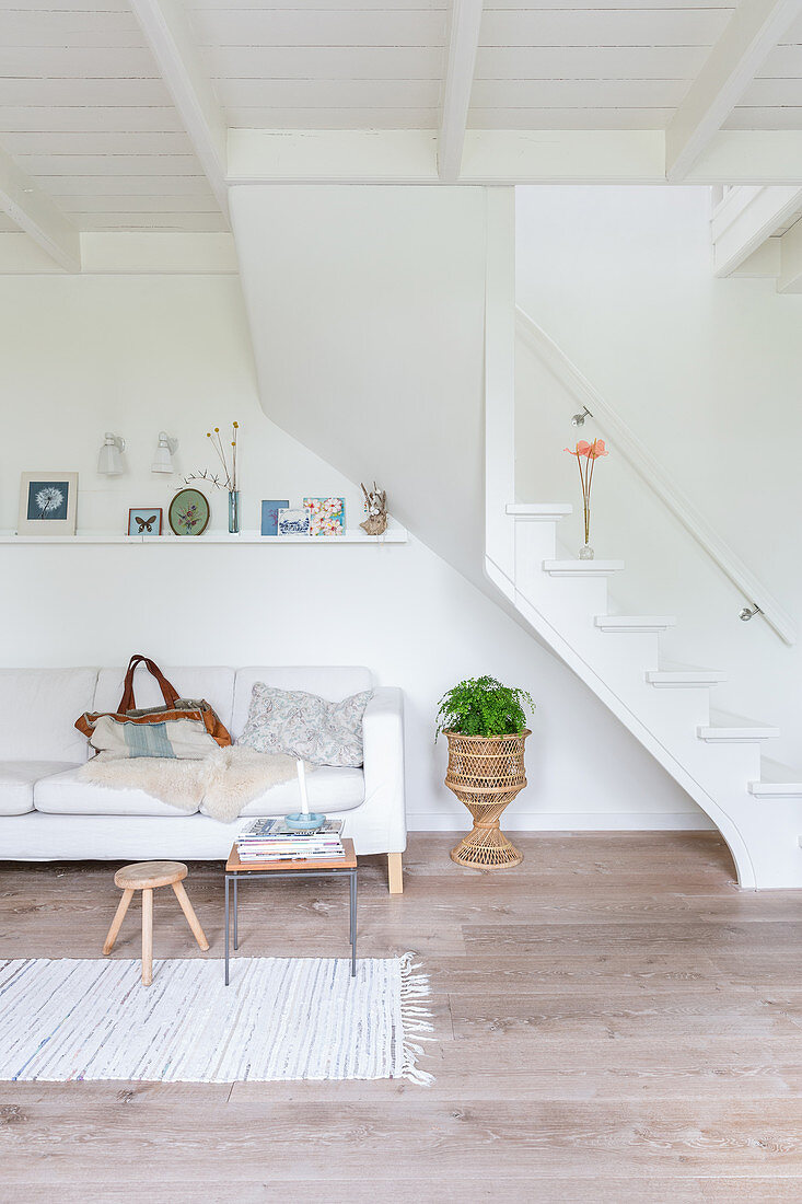 Sofa unter der Treppe im schlichten Wohnzimmer ganz in Weiß