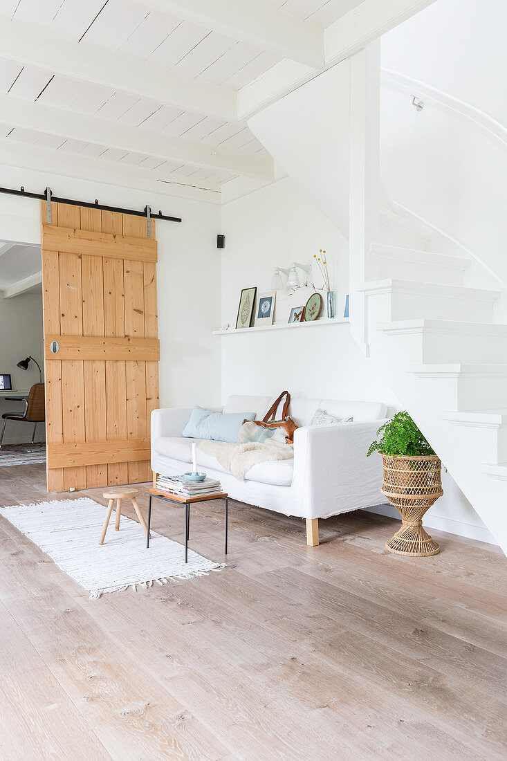 Sofa unter der Treppe vor einer Schiebetür im Wohnzimmer in Weiß