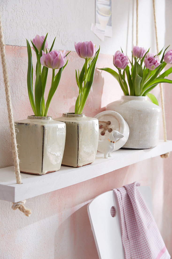Tulips in ceramic vases on shelves