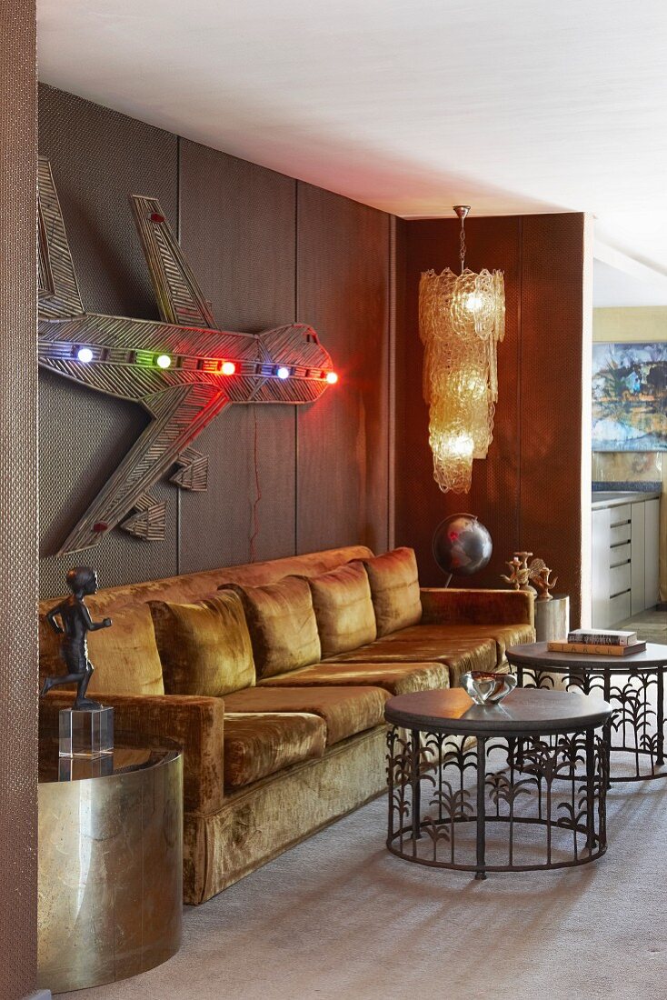 Gold schimmernde Nische mit langem Sofa, Metalltischen und Wandobjekt