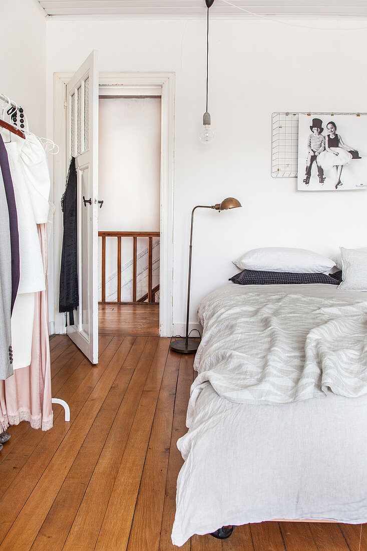 Doppelbett und Kleiderständer im Schlafzimmer mit Holzdielenboden