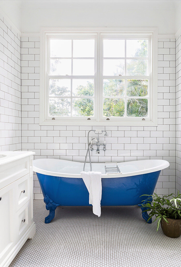 Freistehende blaue Badewanne im schmalen Badezimmer in Weiß