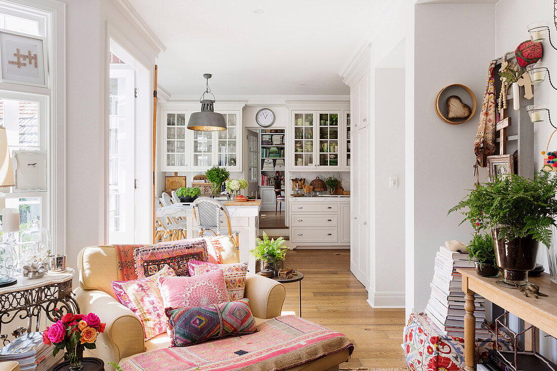 Armchairs with ethnic cushions in front of the open country-style kitchen