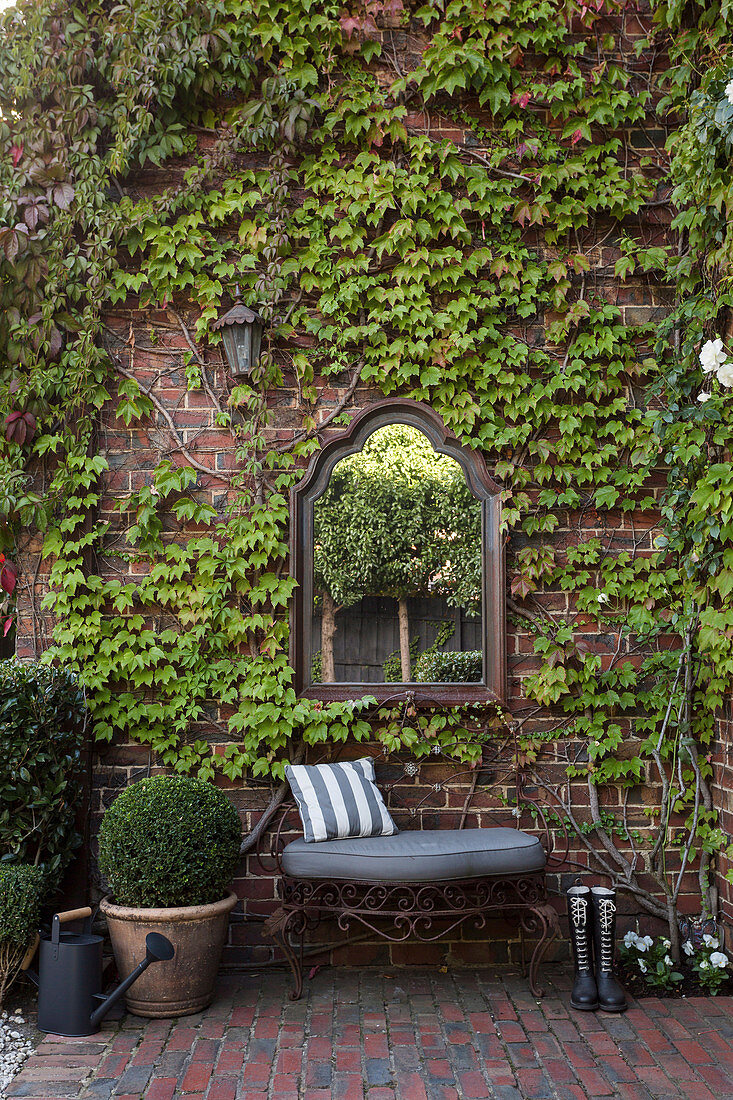 Mirror above the bench on the brick facade with wild wine