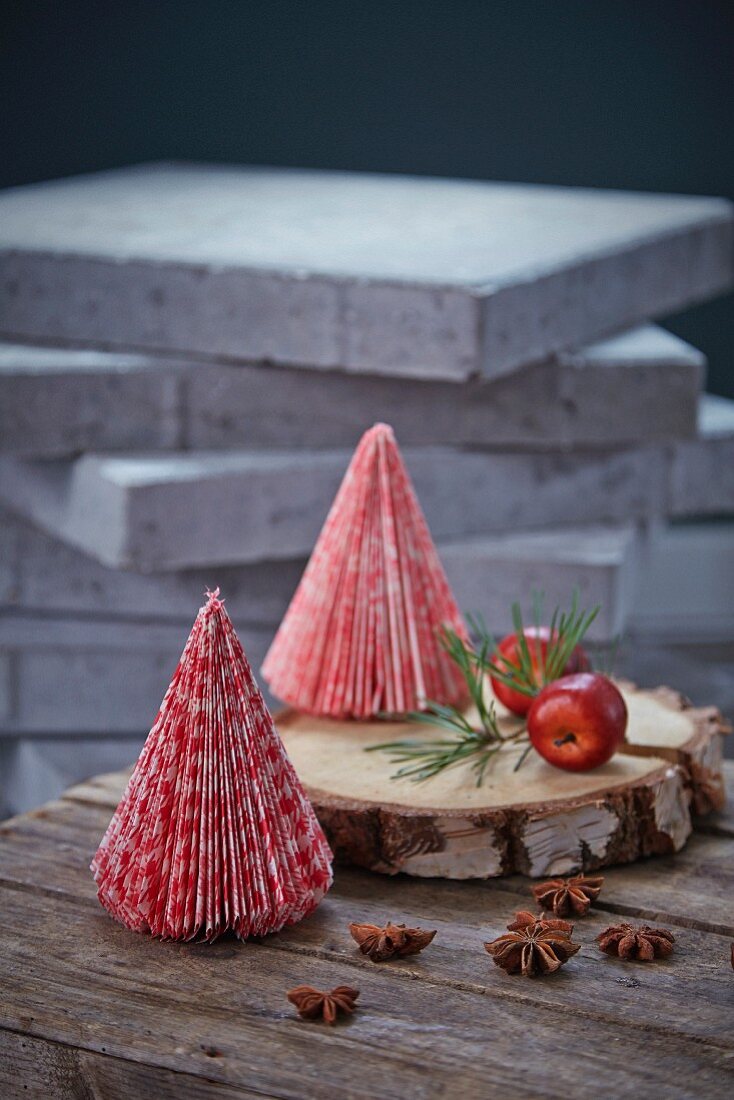 Small red and white paper Christmas trees on slice of tree trunk