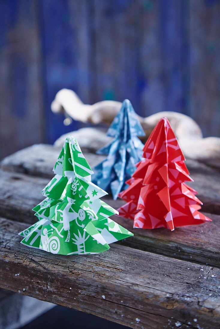 Weihnachtsbäume aus gemustertem Papier auf Holzbrettern