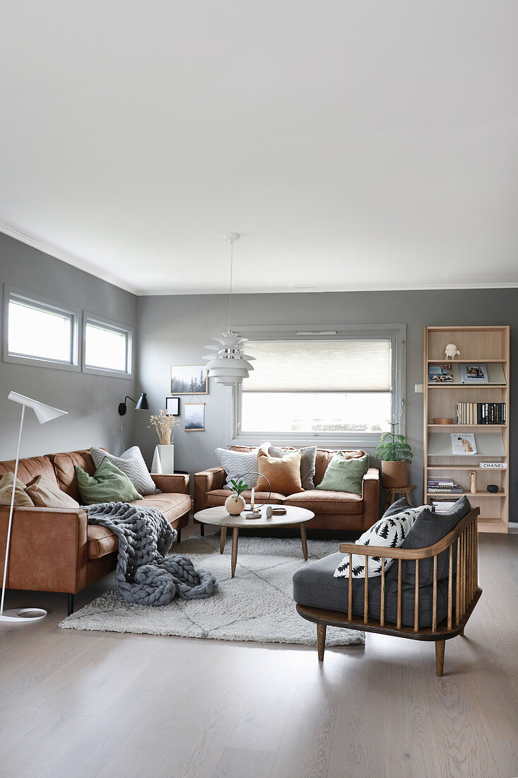 Leather sofas and armchair in cosy living room with grey walls