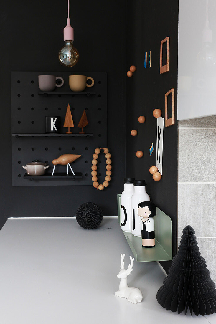 Ornaments on black wall and magnetic pin board in corner of kitchen