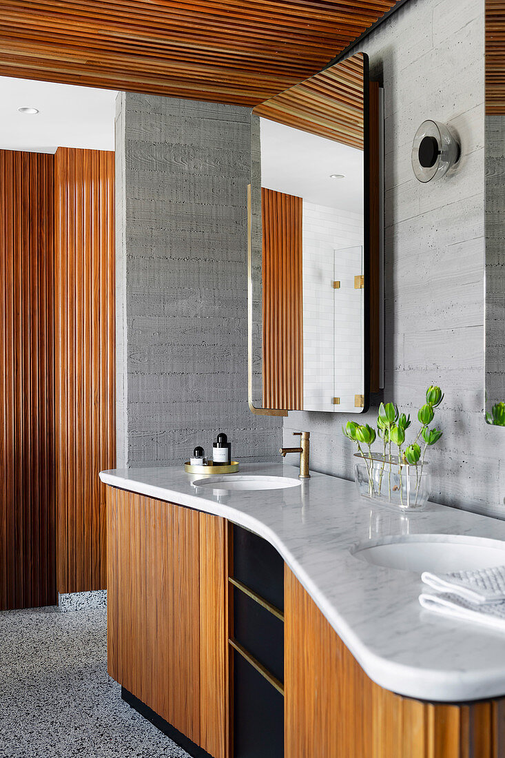 Doppelwaschtisch mit Marmorplatte und Holzfront im Badezimmer mit Wänden in Beton-Optik