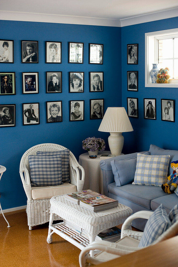 Gallery of black-and-white photos on blue wall, sofa and wicker furniture in living room