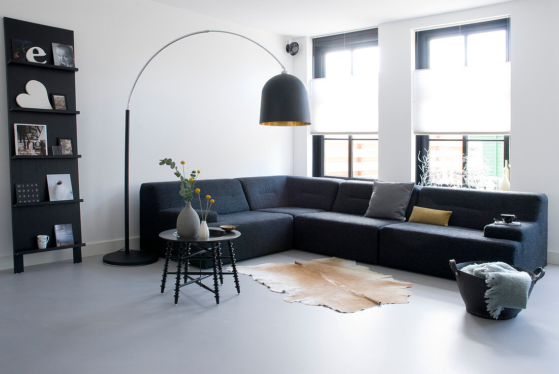 Bogenleuchte überm Sofa im minimalistischen Wohnzimmer in Grautönen