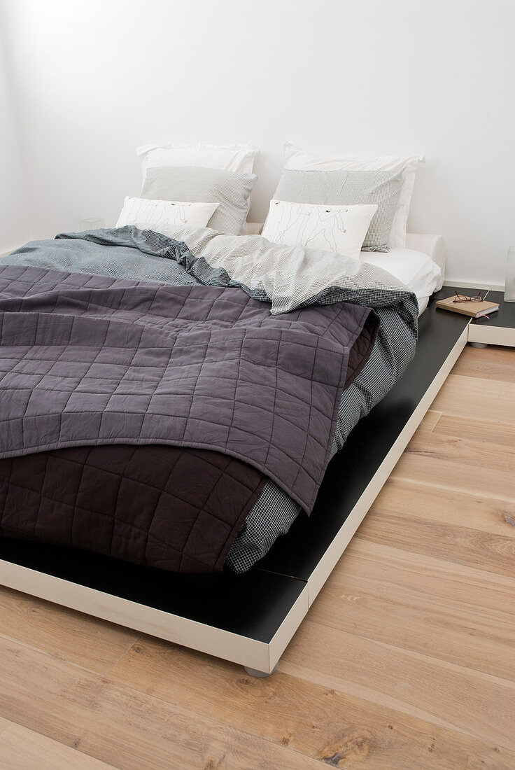 Tiefes Bett im Lagen-Look mit grauer Bettwäsche und Steppdecke