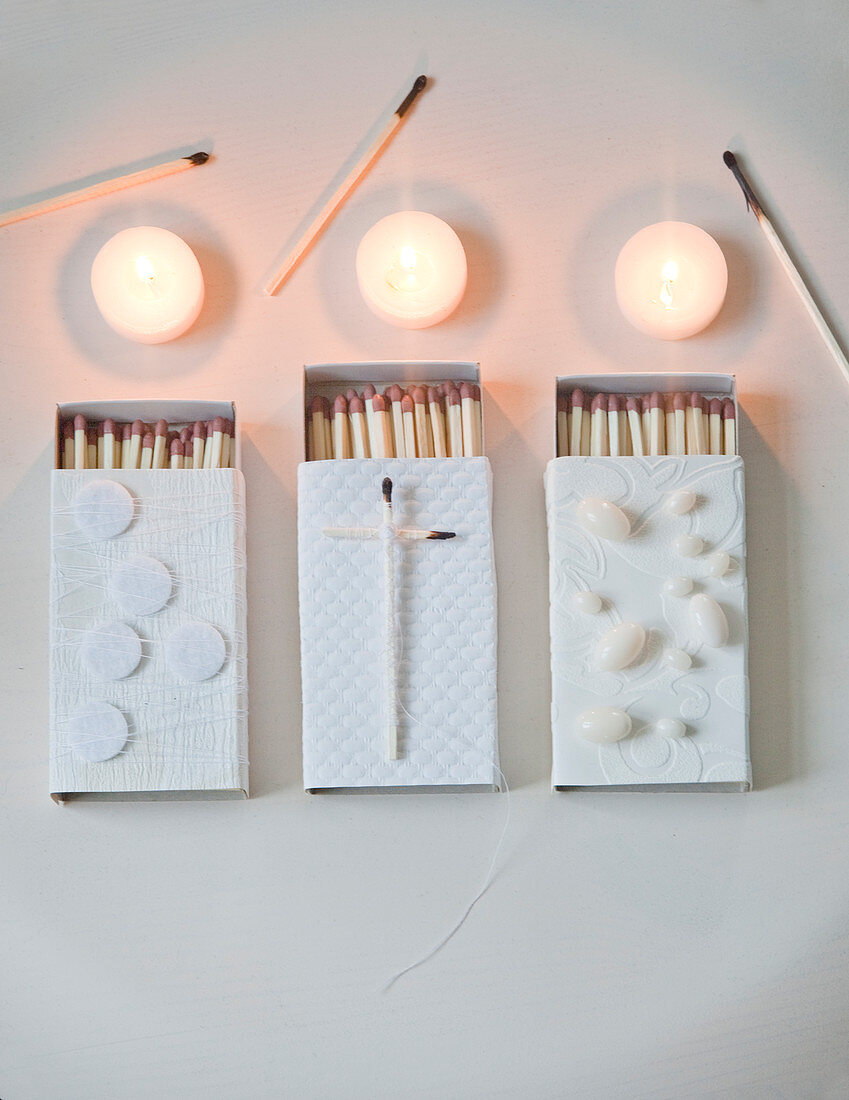 Matchboxes decorated in white, tealights and used matches