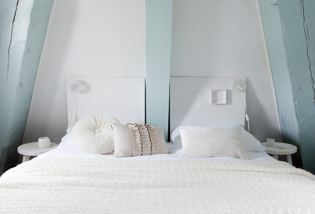 Weißes Doppelbett im Schlafzimmer mit hellblauen Balken