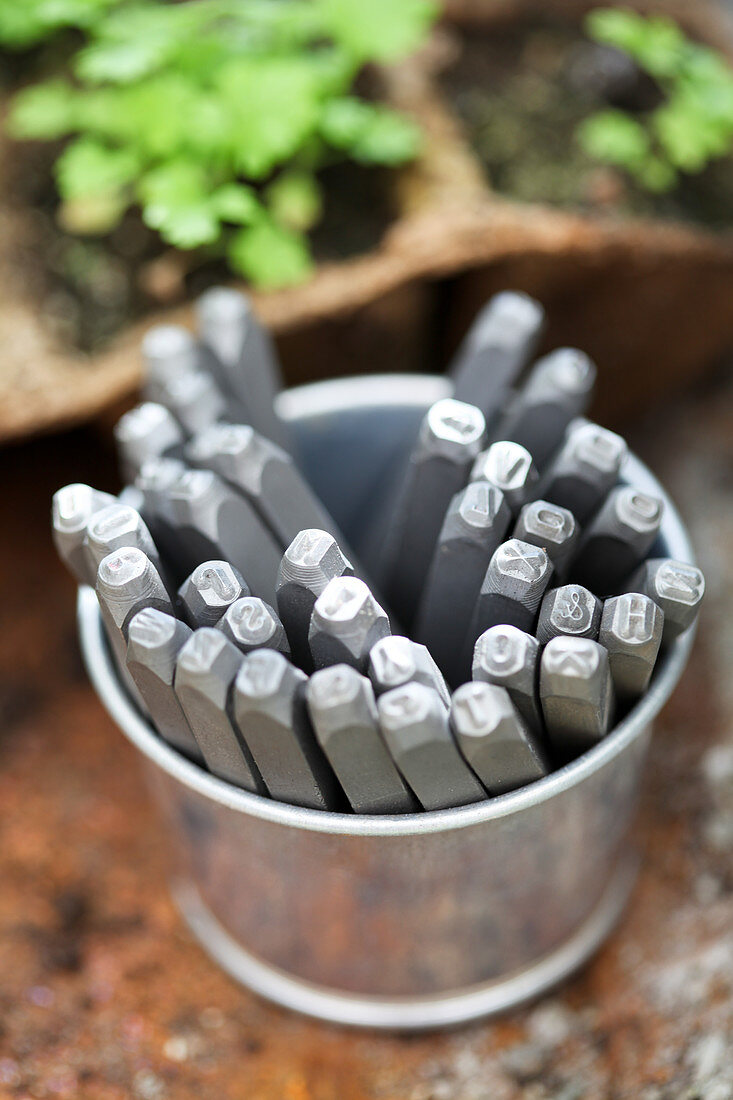 Metal marking punches with letters in metal bucket