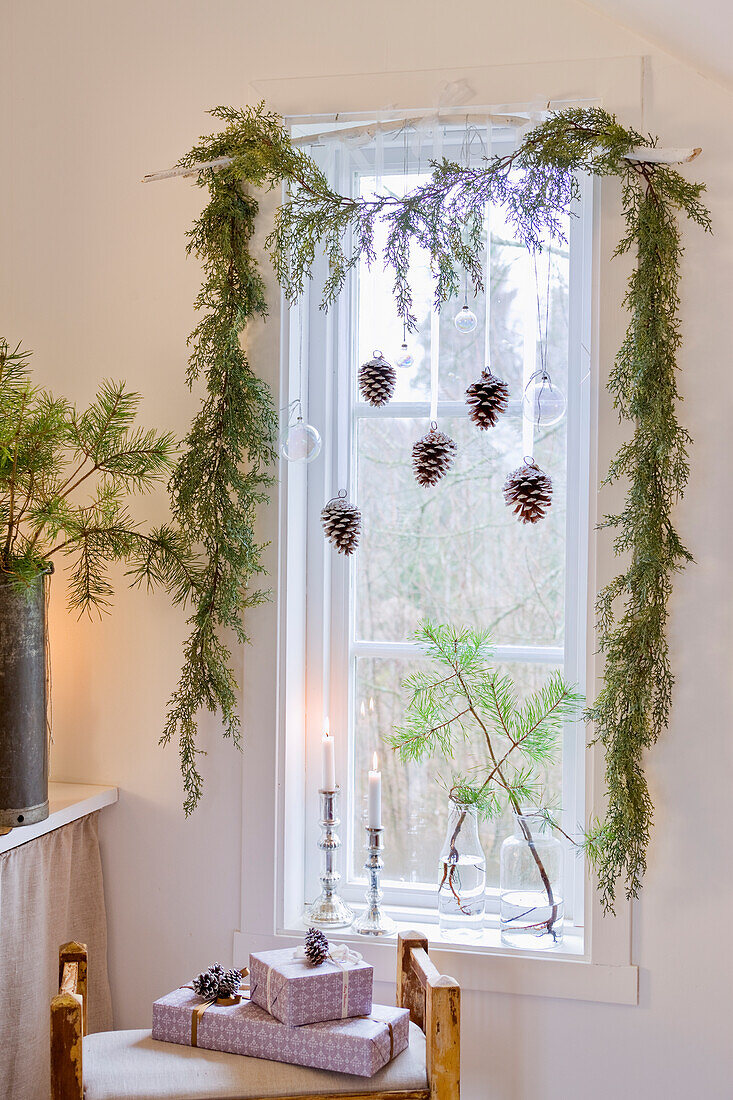 Kleines Fenster mit Weihnachtsgirlande und Zapfen dekoriert