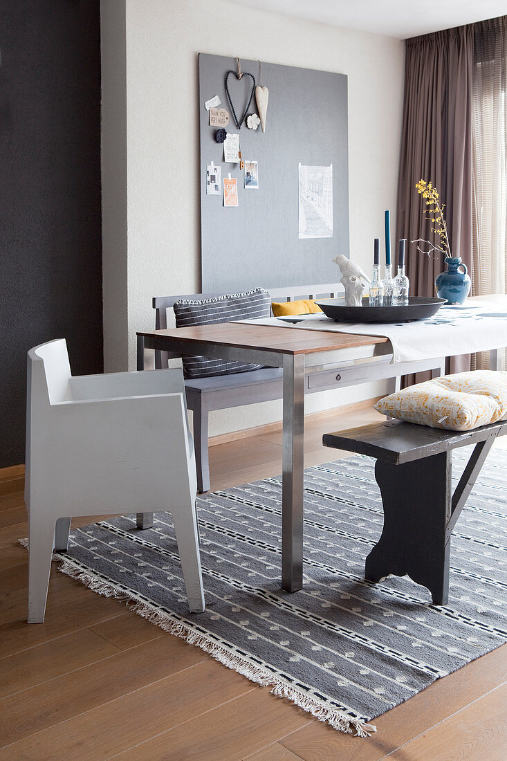 Esstisch mit Designerstuhl und Sitzbänken auf grauem Teppich