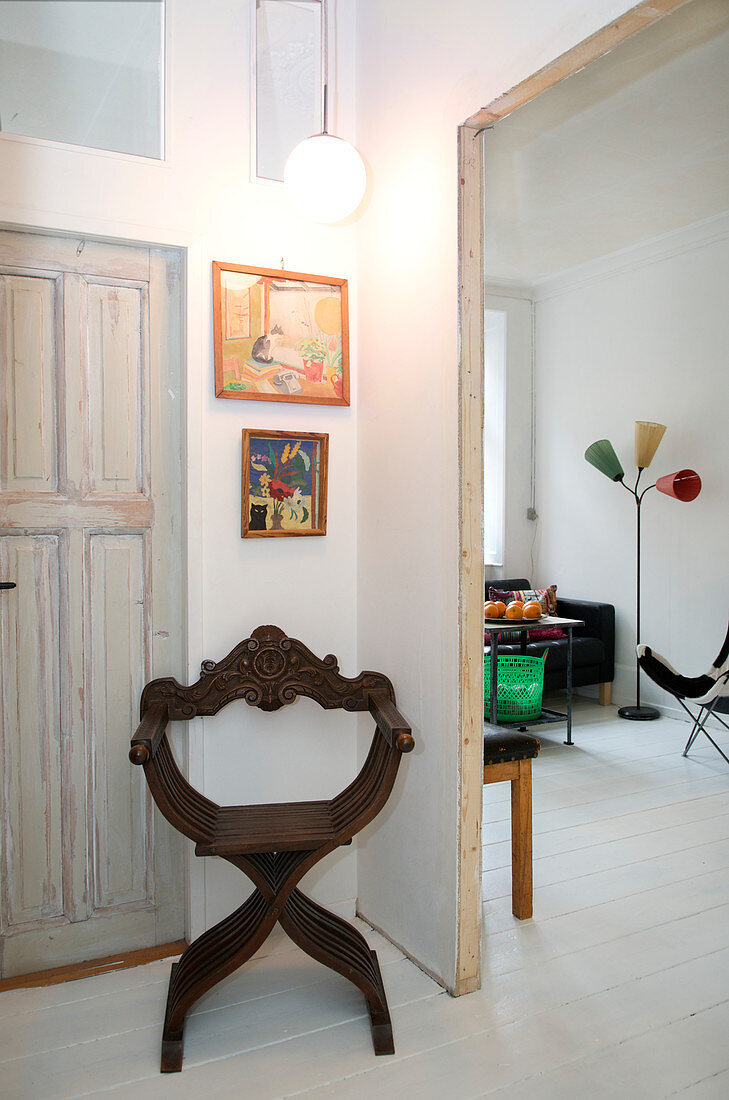 Alter Scherenstuhl vorm Durchgang zum Wohnzimmer mit weißem Dielenboden
