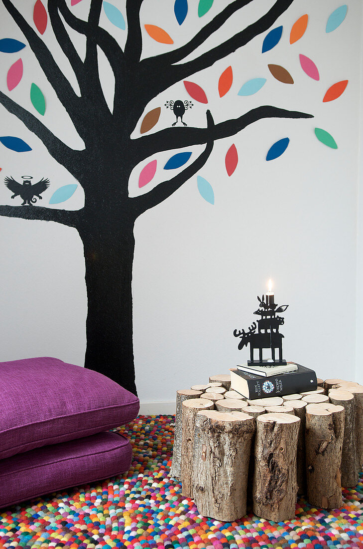 Auf die Wand gemalter Baum und Beistelltisch aus Brennholz