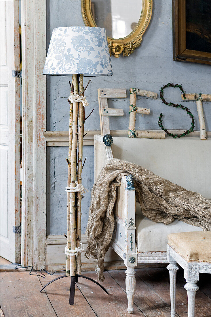 DIY floor lamp made of birch branches next to vintage sofa
