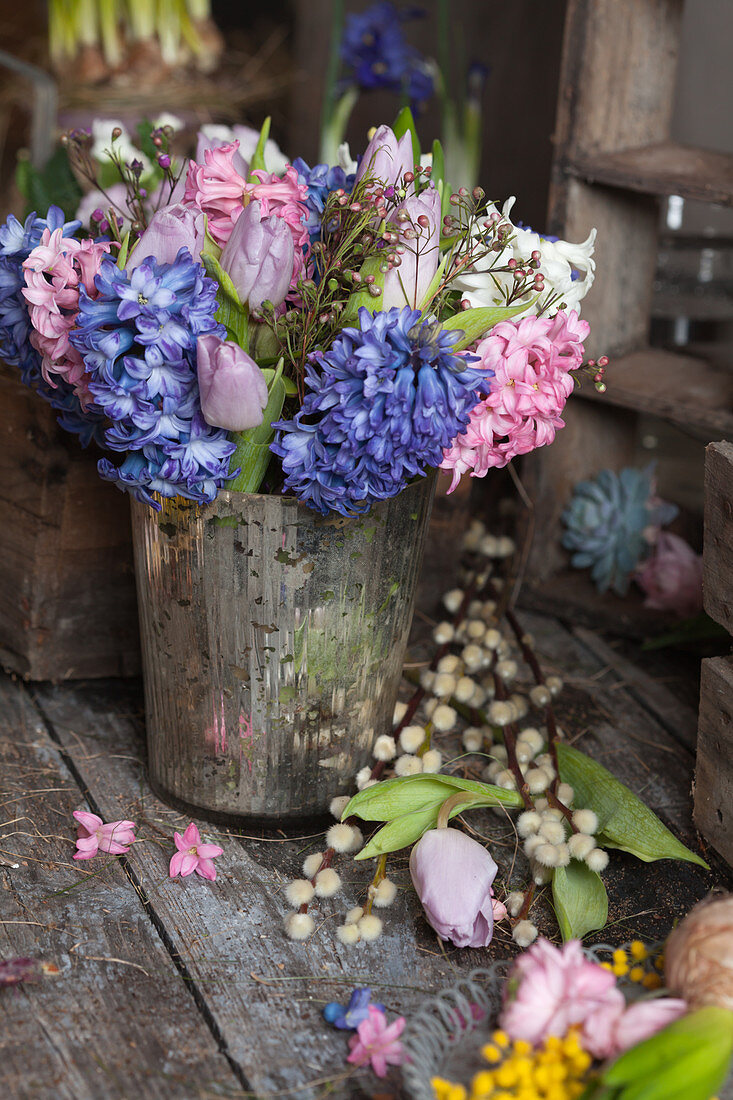 Hyacinths, tulips and Australian waxflowers in silver vase