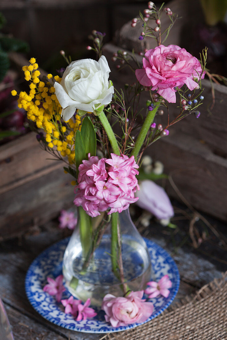 Ranunculus, hyacinths, Australian waxflowers and mimosa flowers in glass vase