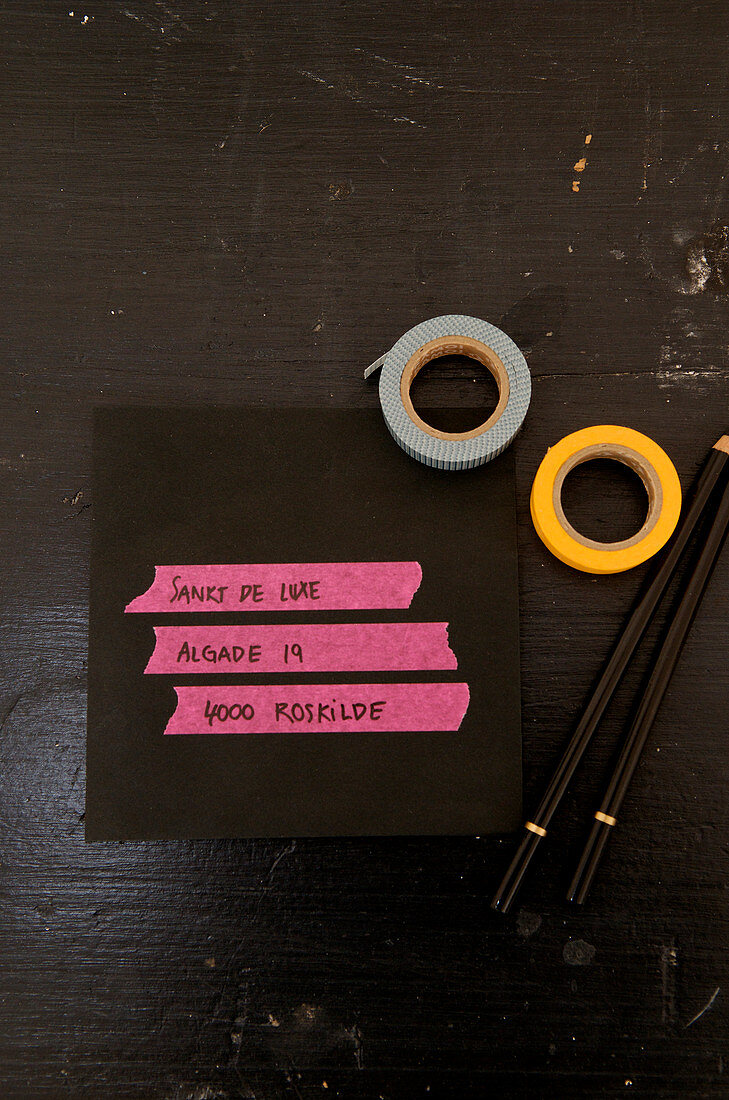 Pinkes Masking Tape mit Adresse auf einem schwarzen Briefumschlag