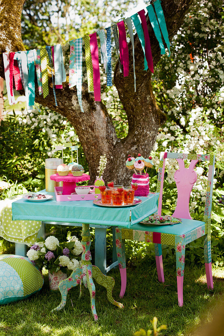 Girlande überm bunt gedeckten Tisch zur sommerlichen Party im Garten