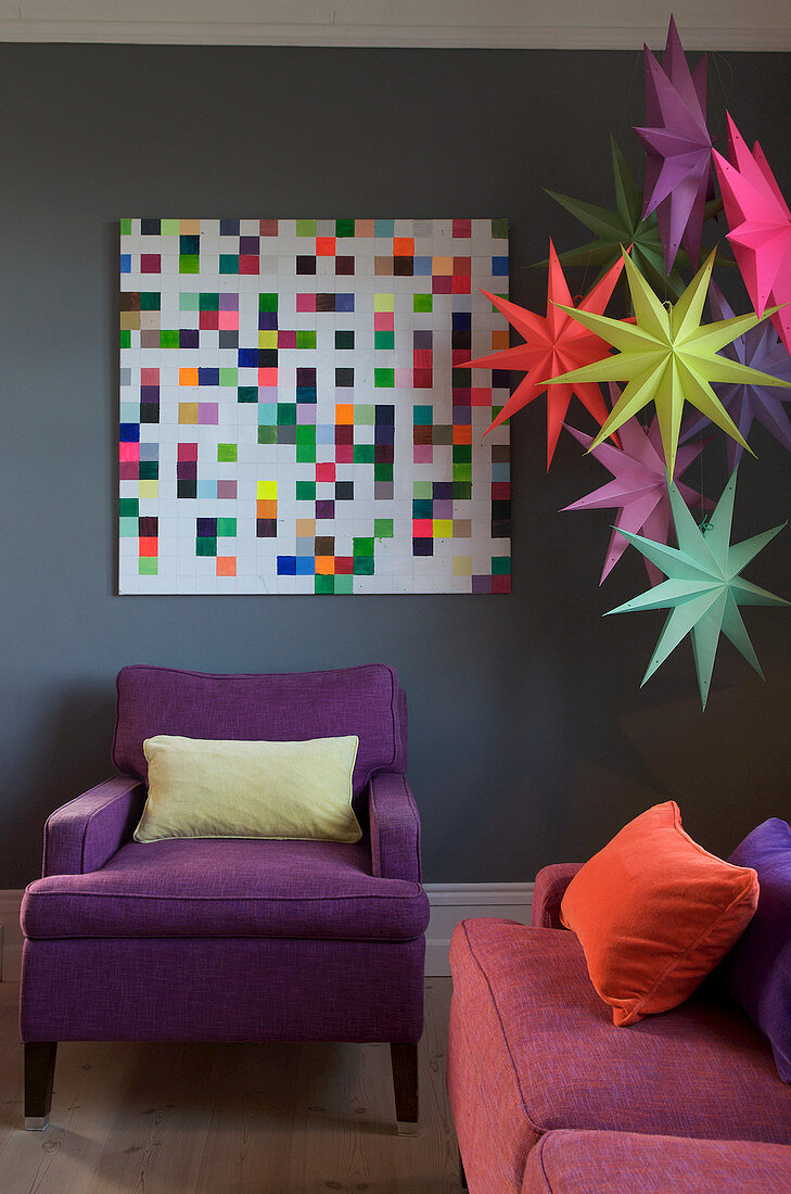 Bunte Papiersterne und Pixel-Bild an grauer Wand im Wohnzimmer