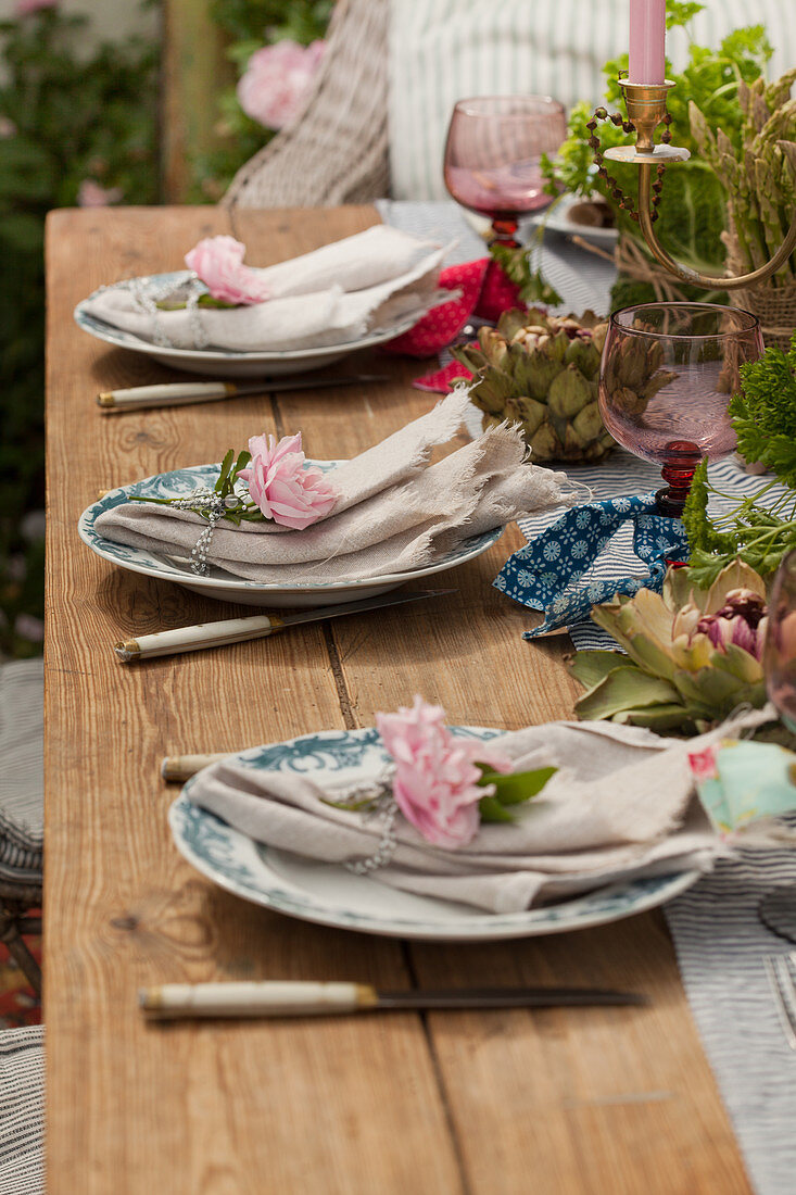 Linen napkins decorated with roses on set table in garden