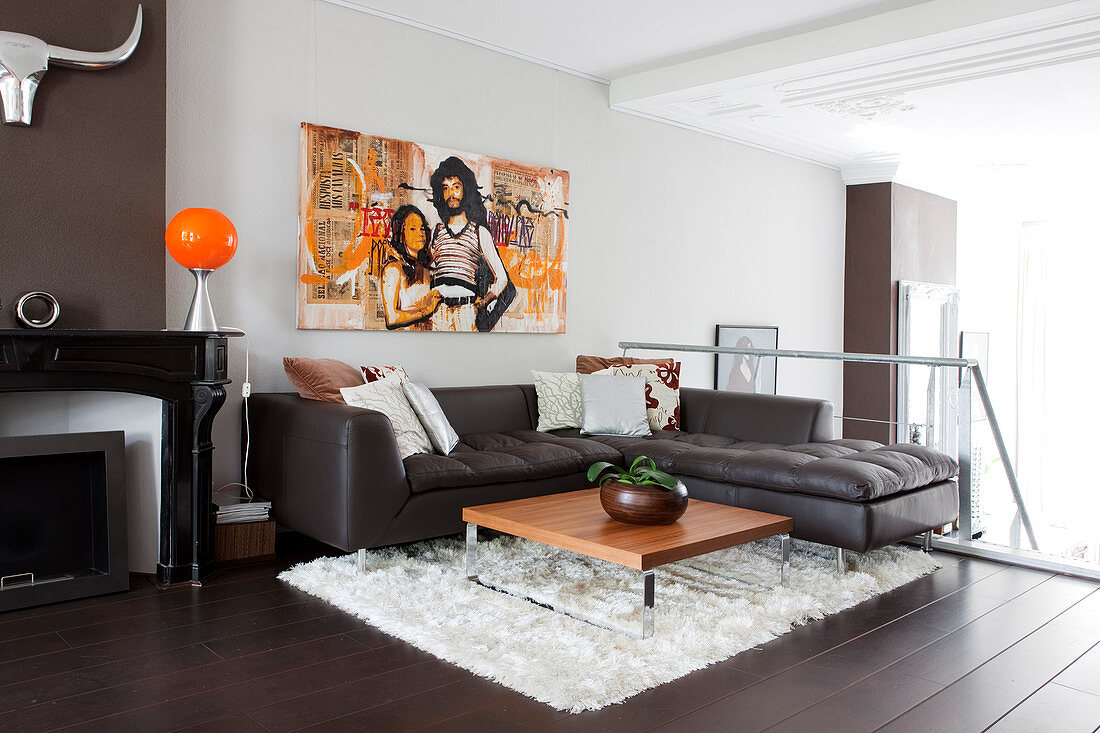 A brow leather couch in a corner with a coffee table on a white carpet and modern art on the wall on the lofted second floor
