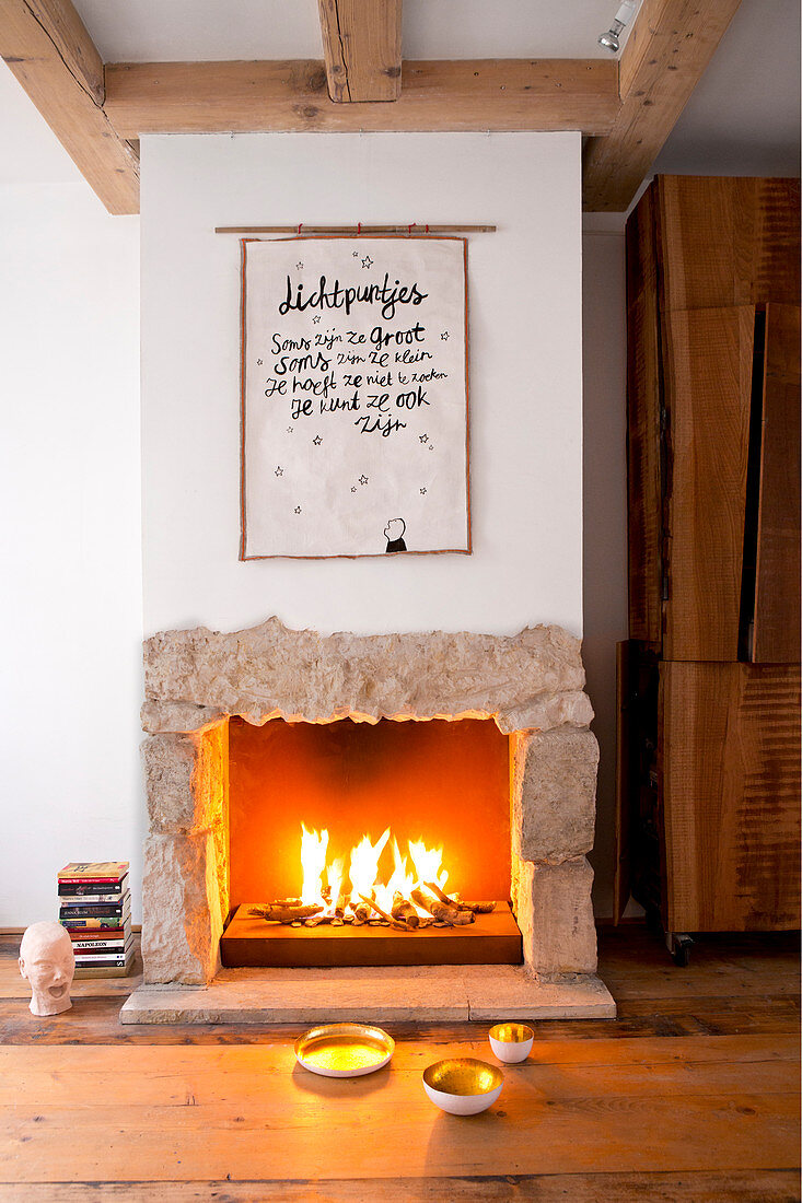 Poster with motto above fire in open fireplace with stone surround
