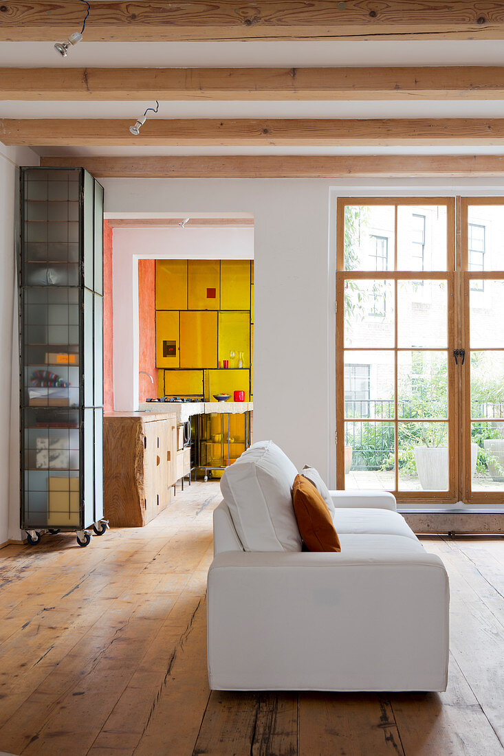 Weiße Couch im Wohnzimmer mit rustikalem Dielenboden und Holzbalkendecke