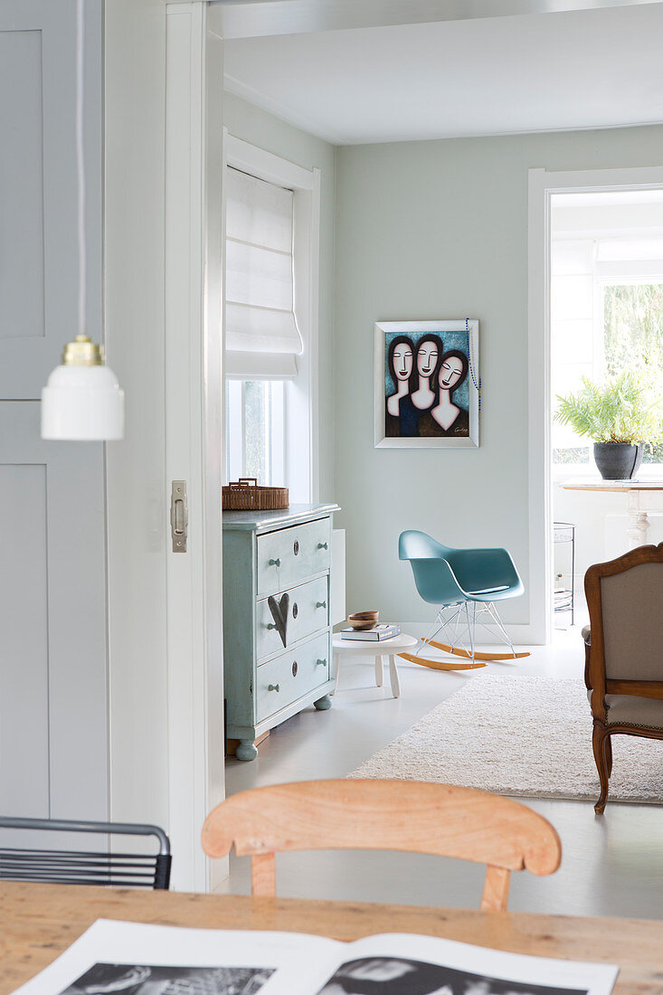 Blick vom Esstisch ins Wohnzimmer in gedeckten Farben mit Schaukelstuhl