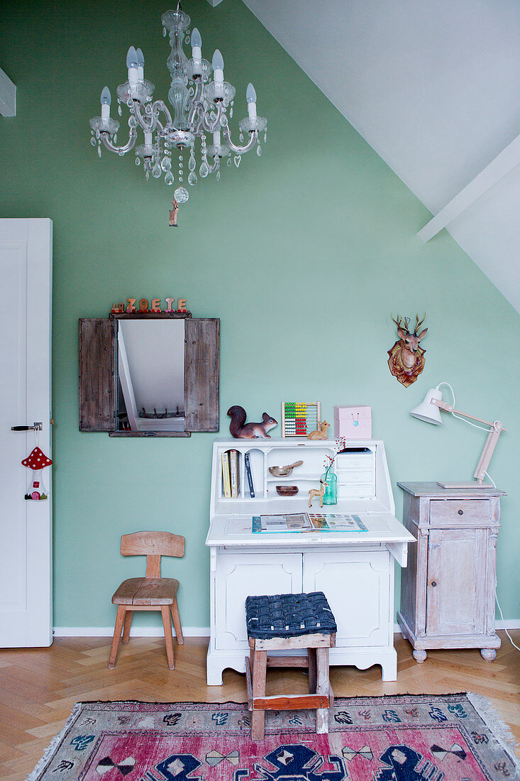 Child-sized bureau against green wall under sloping ceiling