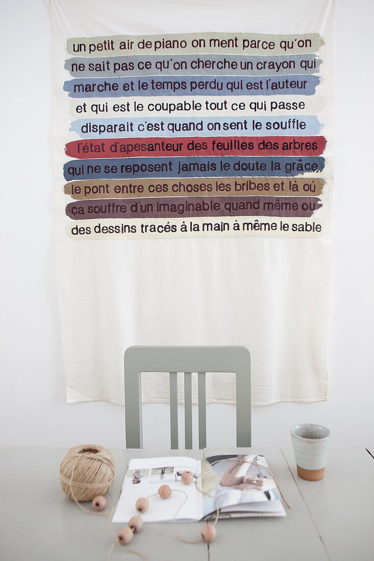 Table with crafting materials, behind it a wall hanging with a message