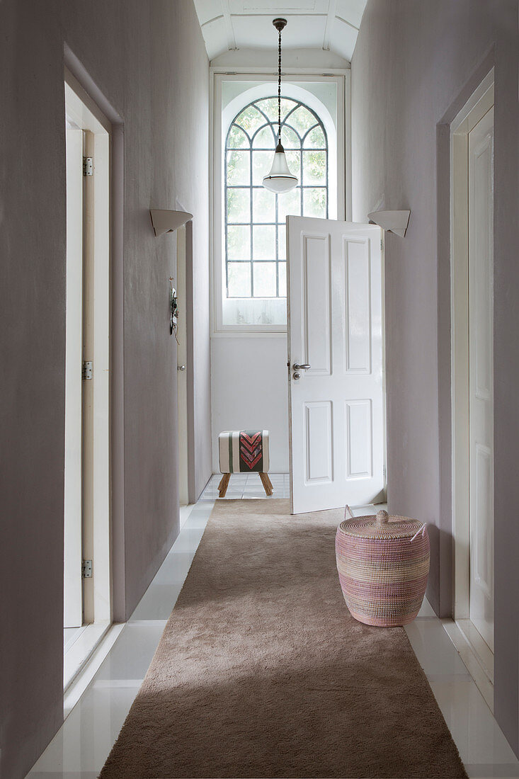 Brown runner in hallway with high ceiling and arched window