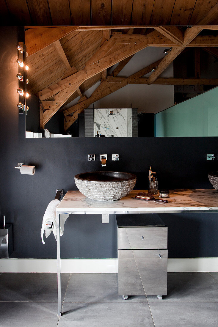 Washstand in rustic bathroom with black wall and wood-beamed ceiling