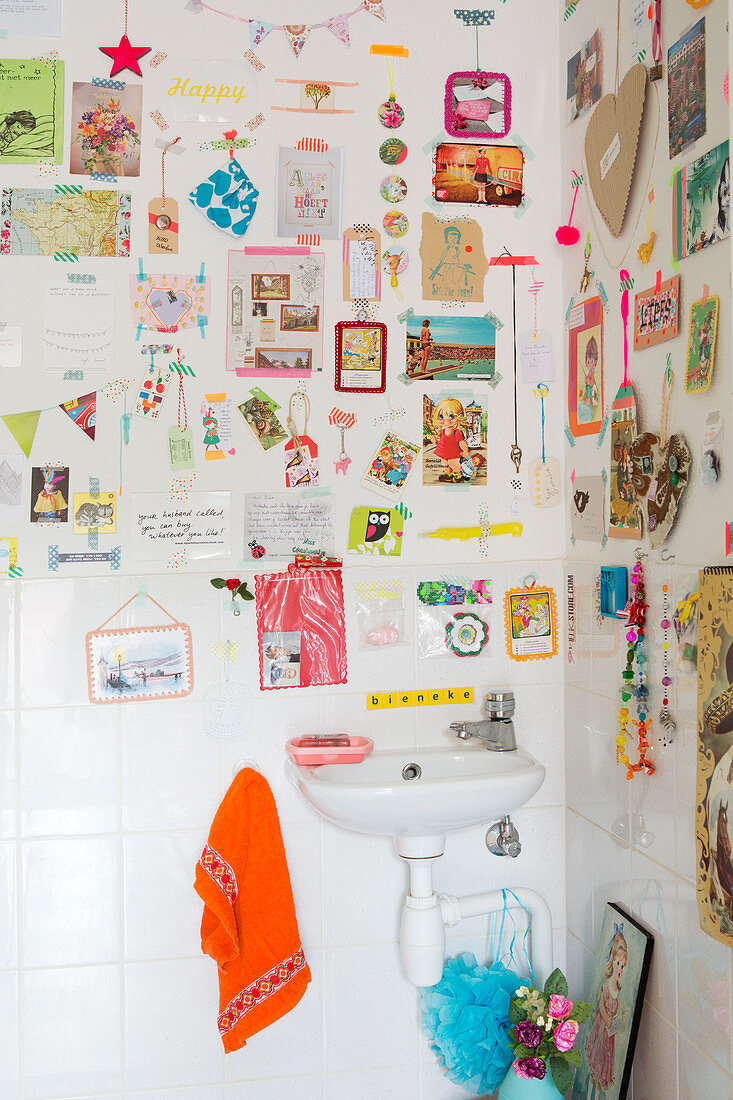 Bunt beklebte Wand mit Bildern und Masking Tape über dem Waschbecken