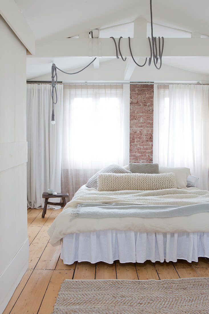 Layered blankets on a bed with a dust ruffle in the bright bedroom